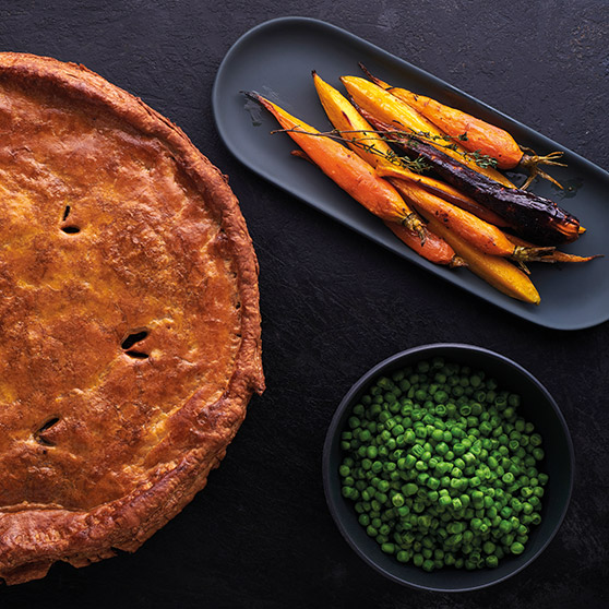 Pastel dorado, zanahorias asadas de colores y guisantes verdes – preparados profesionalmente con el CHEF'S COMBI de HOBART para un dorado perfecto y cocción uniforme.