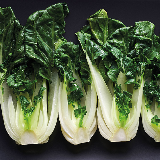 Cuatro piezas de bok choy fresco con tallos blancos y hojas verdes – cocinadas suavemente con el CHEF'S COMBI de HOBART para conservar frescura y nutrientes.