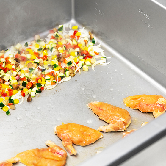 Interior de una HOBART Precipan con verduras troceadas y ave dorada, equipo multifuncional de tecnología de cocción para cocinas profesionales.
