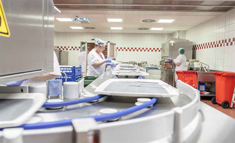 Moderna zona de lavado con HOBART FLOW Line autoLINE, sistema de lavado automático con cinta transportadora y estaciones de trabajo para limpieza eficiente de bandejas, platos y vasos, estructura de acero inoxidable para procesos higiénicos y optimizados.