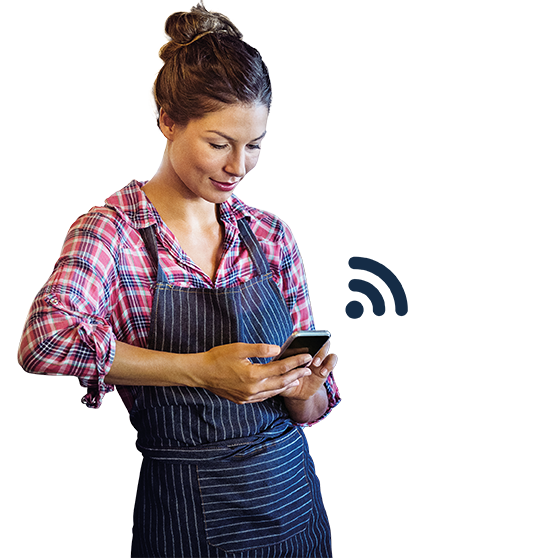 Persona con ropa de trabajo utilizando un smartphone para gestionar equipos de cocina mediante Smartconnect, con icono de conexión inalámbrica, ideal para conectividad digital y gestión eficiente en hostelería.