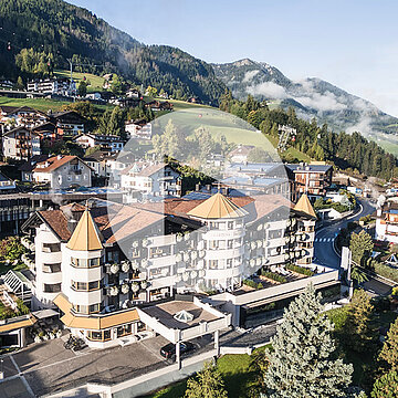 Vista aérea del Gardena Grödnerhof en Ortisei, un hotel de cinco estrellas Relais & Châteaux rodeado del paisaje de los Dolomitas, conocido por su restaurante gourmet Anna Stuben, distinguido con una estrella Michelin y valoraciones destacadas de guías reconocidas.